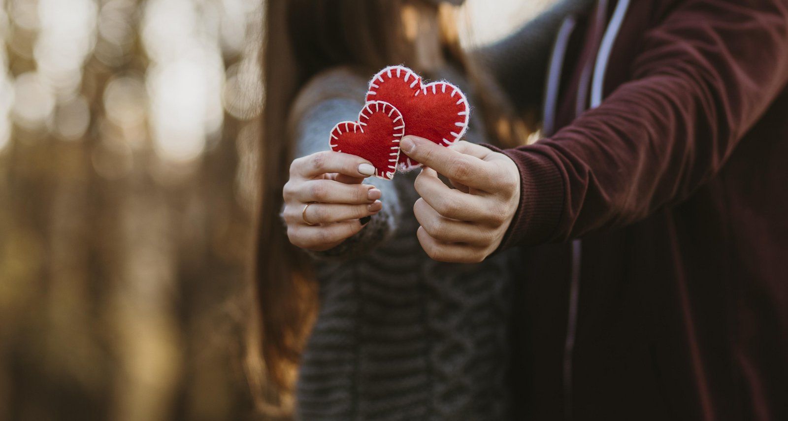 Ein Liebespaar hält zwei rote Herzen in der Hand zum Valentinstag