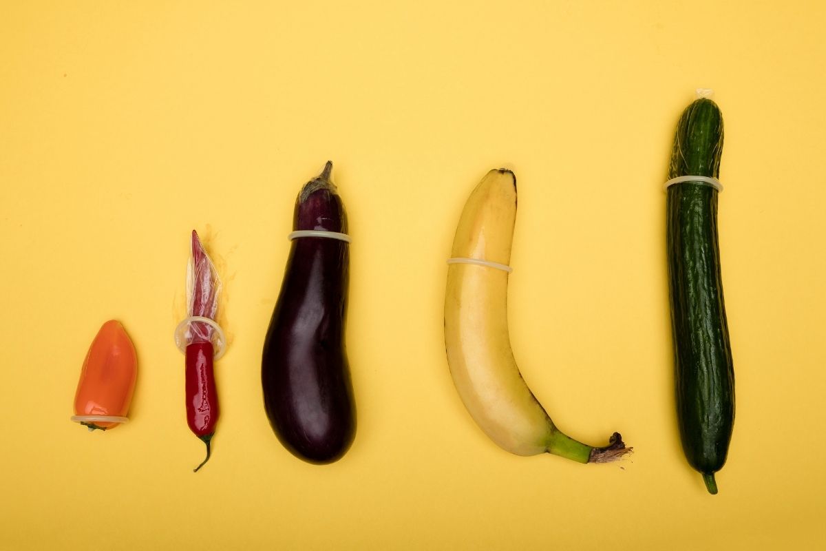 Kondome auf unterschiedlich großem Obst und Gemüse